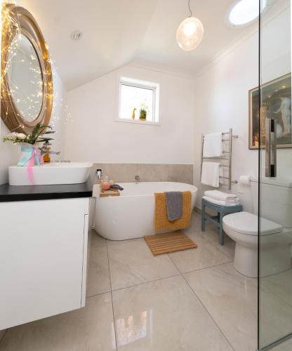 a bathroom with a tub and a toilet and a sink at The Greytown Loft in Greytown