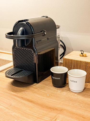 a coffee maker sitting on a table with two cups at ADORNO PRIVATE SUITES Only Adults & Kids 12 Plus in Nea Vrasna