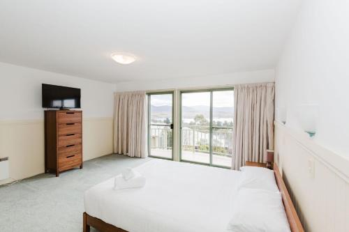 Un dormitorio con una cama y una ventana grande. en Glacialis 4, en Jindabyne