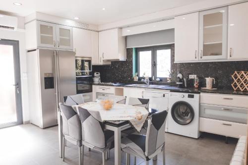 a white kitchen with a table and chairs and a dishwasher at Vivenda à Beira Rio in Folgosa