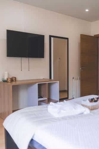 a bedroom with a bed with a flat screen tv on the wall at Vivenda à Beira Rio in Folgosa