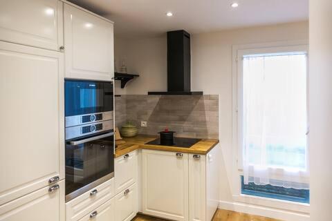 une cuisine avec des placards blancs et une grande fenêtre dans l'établissement Cosy flat Paris 14, à Paris