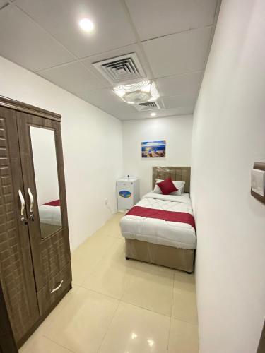 a small bedroom with a bed and a mirror at Luxury Private Rooms for Men in Sharjah