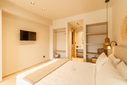 a bedroom with a large white bed and a television at ADORNO PRIVATE SUITES Only Adults & Kids 12 Plus in Nea Vrasna