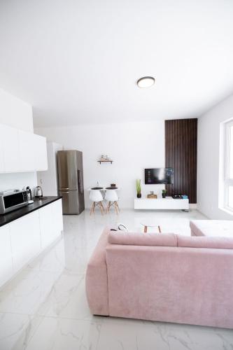 a living room with a pink couch and a kitchen at Novostavba v centre + parking in Banská Bystrica