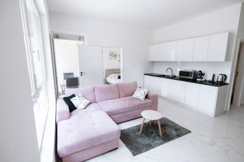 a living room with a pink couch and a kitchen at Novostavba v centre + parking in Banská Bystrica