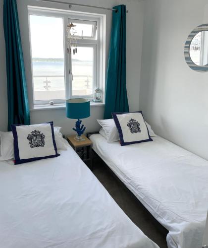 two twin beds in a room with a window at Sandbanks, Poole Harbour in Sandbanks