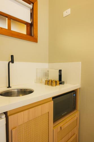 a kitchen counter with a sink and a microwave at FLAT 3-107 - Iha Flat Hotel - Pereque - Ilhabela in Ilhabela