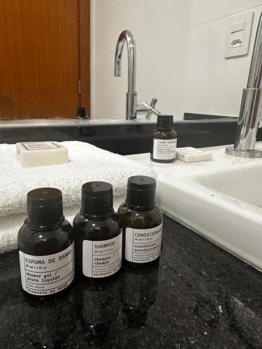 three bottles of medicine sitting on a counter next to a sink at Venda Nova Apart in Venda Nova do Imigrante