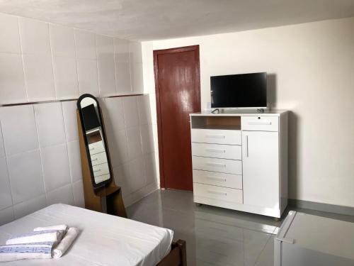 a room with a bed and a tv on a dresser at Suite Diamantina in Diamantina