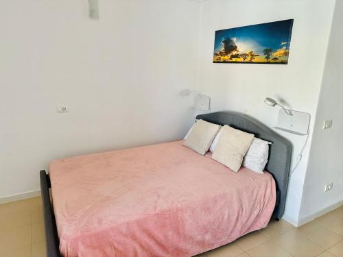 a bedroom with a bed with pink sheets and two lamps at Apartamento Vacacional Isabella in San Miguel de Abona