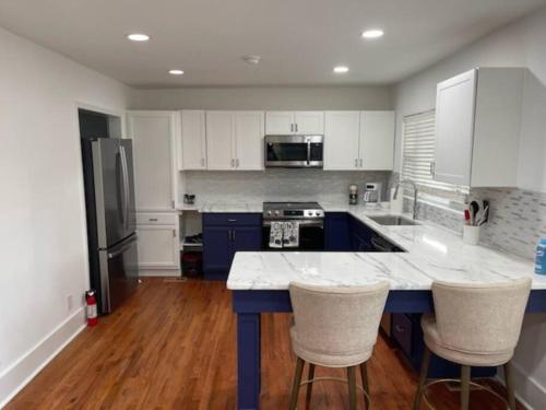 a kitchen with white cabinets and a blue island with bar stools at Charming Family Retreat in Augusta