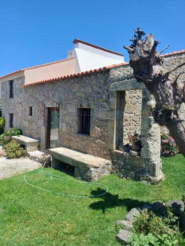 a stone building with a bench in the grass at O Celeiro - Espaço Rural in Tougues