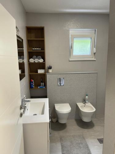 a bathroom with a sink and a toilet and a window at House and pool BajNa in Mostar