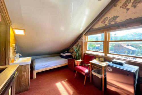 a small room with a bed and a sink and a window at Fireside Inn & Hostel in Breckenridge