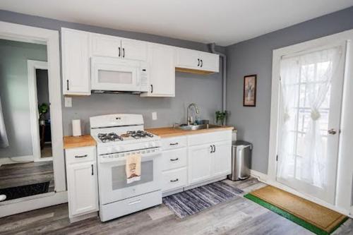 a kitchen with white cabinets and a white stove at Cozy Haven at the footsteps of Harbor East in Baltimore