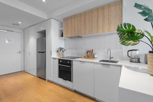 a white kitchen with a sink and a dishwasher at Complete Host STK Apartments in Melbourne