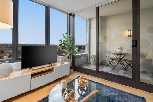 a living room with a flat screen tv and large windows at Complete Host STK Apartments in Melbourne