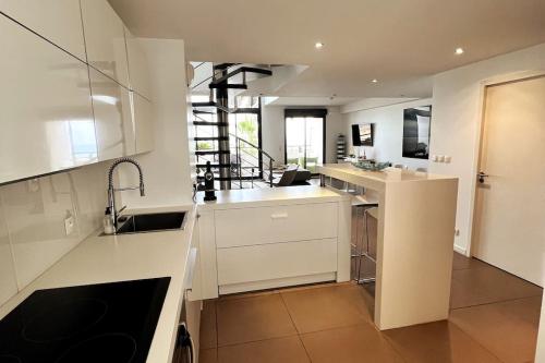 une grande cuisine avec des comptoirs blancs et un évier dans l'établissement Le Nid du Lido, à Sète