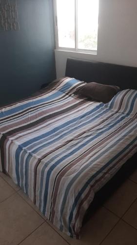 a bed with a striped blanket on top of it at Liverte Cancun in Cancún
