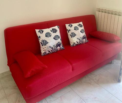 a red couch with two pillows on it at Casa ORI in Montesilvano