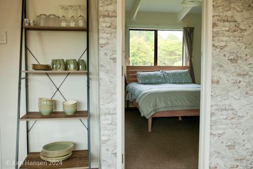 a bedroom with a bed and a window at Mill Creek Cottage in Coroglen