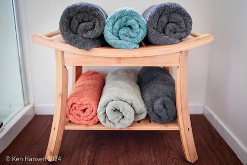 a wooden shelf with different colored towels on it at Mill Creek Cottage in Coroglen