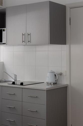 a kitchen with white cabinets and a toaster on the counter at MAC St Kilda Acland St by Melbourne Apartment Collection in Melbourne