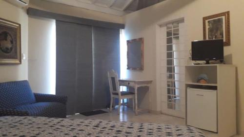 a bedroom with a bed and a desk and a television at Recanto Serenissima in São Pedro