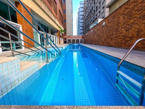 a swimming pool in a building with blue water at Estanconfor Vista Mar comGaragem Arrumação Diária, Ar Cond. e Cozinha in Santos
