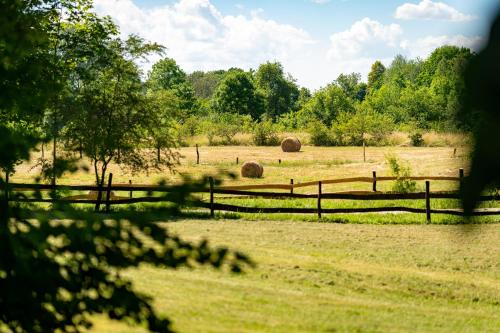 two hay bales in a field behind a fence at Pilwa 17 - Glamping na Łące in Węgorzewo