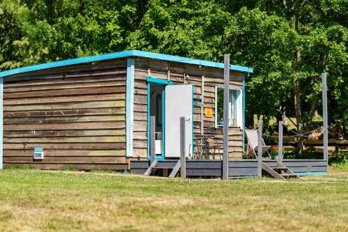 a small cabin with a blue roof and a door at Pilwa 17 - Glamping na Łące in Węgorzewo