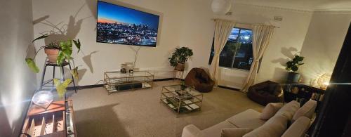 a living room with a couch and a tv on the wall at Nest at Maggies in Melbourne