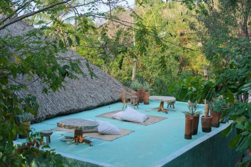 a patio with two tables and chairs and trees at Monte Uzulu Boutique Hotel in San Agustinillo