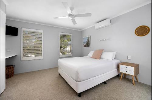 Un dormitorio blanco con una cama blanca y dos ventanas. en Seychelles 2 - Short stroll to Noosa River, en Noosaville