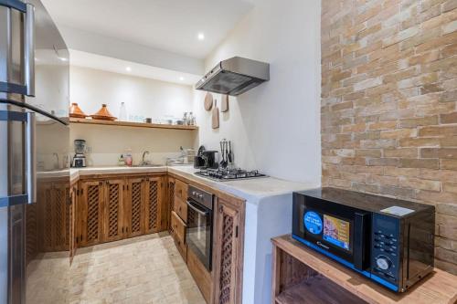 a kitchen with a stove and a microwave at Riad Zatiah Exclusive and chic breakfast incl in Marrakech