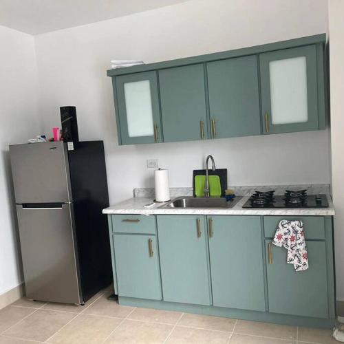 a kitchen with blue cabinets and a refrigerator at Sweet Sunset 5 Playa Rompeolas, Aguadilla in Aguadilla