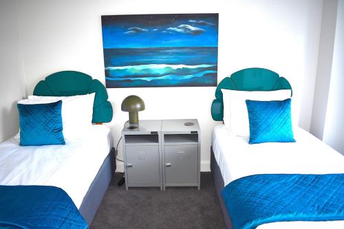 two beds in a room with blue and white at 6 on Adams in Mount Maunganui