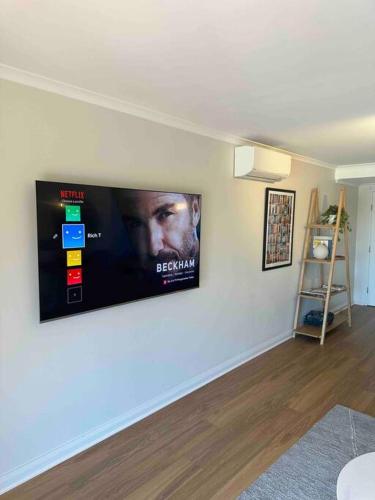 a flat screen tv on a wall in a living room at City fringe modern apartment with car parking in Hobart