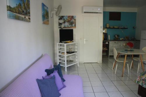 a living room with a purple couch and a table at Le Colibri et le Frangipanier in La Trinité