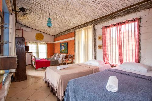 a bedroom with two beds and a living room at Pousada Encanto das Águas in Ilhabela