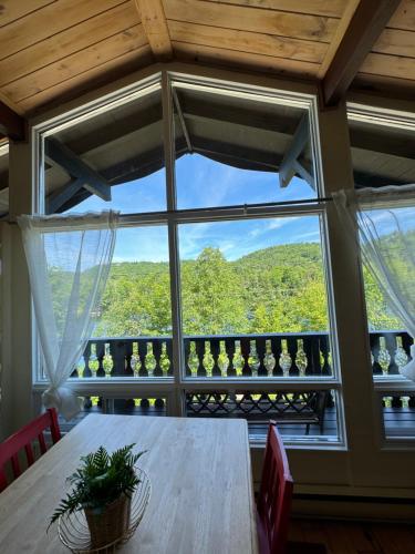 a dining room with a table and a large window at Chalet Alpin Suisse Au Bord Du Lac in Morin Heights