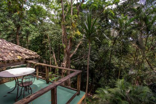 a balcony of a house in the jungle with a table at Pousada Encanto das Águas in Ilhabela
