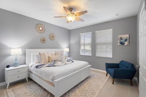 a bedroom with a bed with a ceiling fan and a blue chair at Lux 4BrVilla Hot Tub Grill Private Heated Pool in Kissimmee