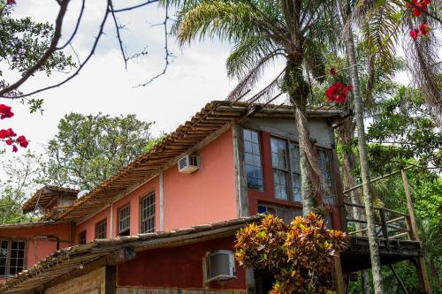 a red house with a palm tree in front of it at Pousada Encanto das Águas in Ilhabela