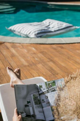 a person reading a book next to a swimming pool at Noosa Heads Motel in Noosa Heads