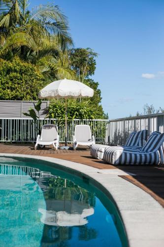 a swimming pool with two lounge chairs and an umbrella at Noosa Heads Motel in Noosa Heads