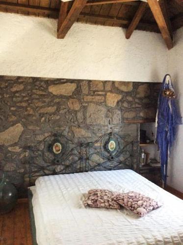 a bed in a room with a stone wall at Summer Stoned Maisonette in Kondiás
