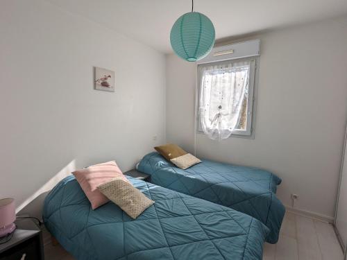 - une chambre avec 2 lits bleus et une fenêtre dans l'établissement Arcachon - Superbe T3 avec terrasse, piscine et parking sécurisé - 6 personnes - FR-1-420-33, à Arcachon
