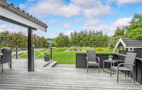 a deck with chairs and a table and a playground at Holiday Home Jægerens Vej in Blokhus